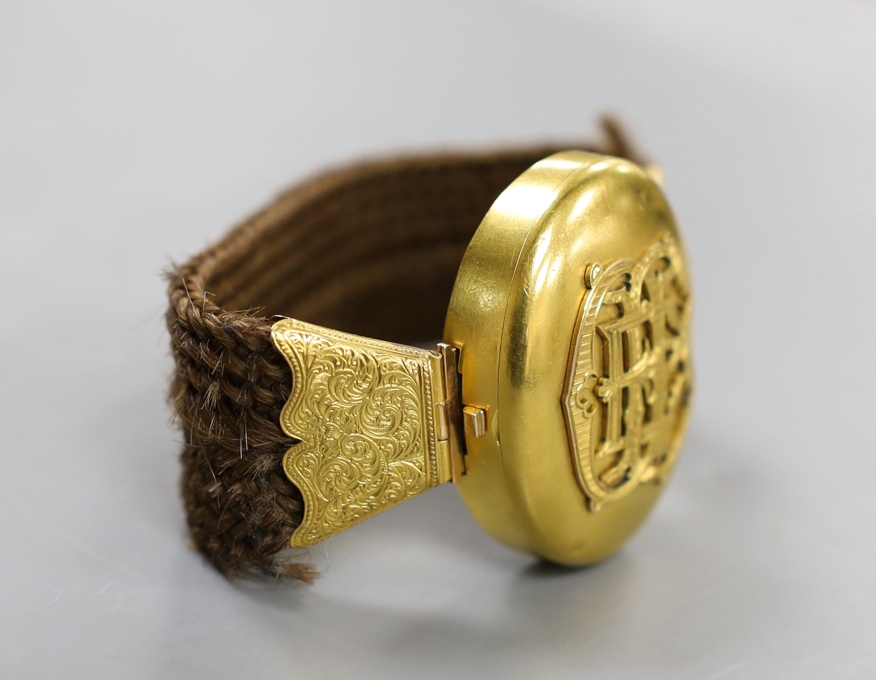 A Victorian yellow metal and hairwork bracelet with central photographic locket, central motif 44mm, gross weight 35.3 grams.